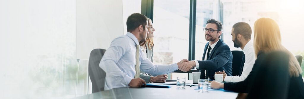 Colleagues shaking hands across a table at the end of a meeting