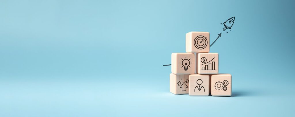 Wooden blocks printed with planning icons stacked against a pale blue background