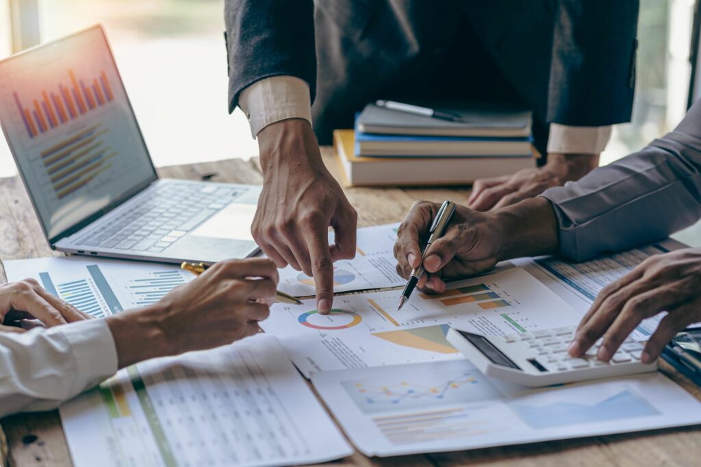 Hands pointing at printed charts beside a laptop during a planning session